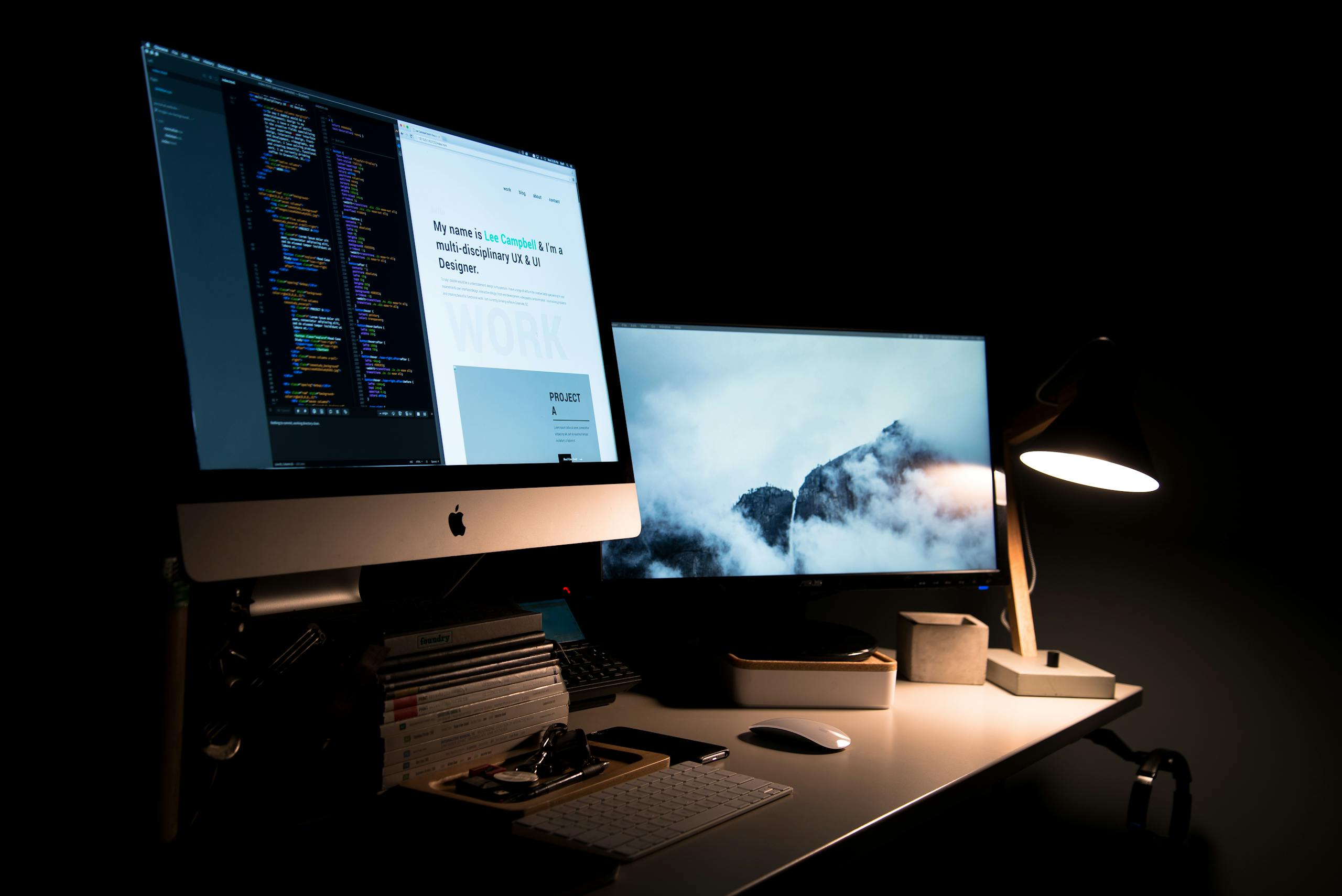 A clean and stylish workspace featuring dual monitors, a lamp, and office supplies.